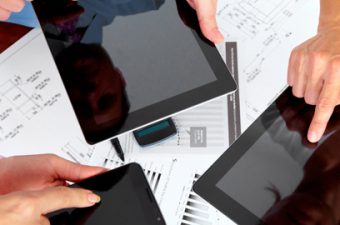 três mãos apontam para a tela do tablet