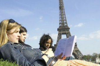 Jovens estudando deitados na grama em frente à torre Eiffel, na França