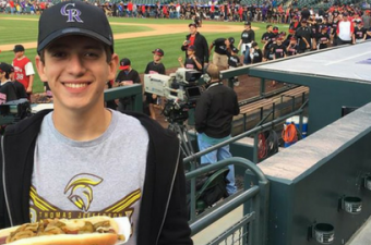 jovem com cachorro quente assistindo jogo de futebol em estádio