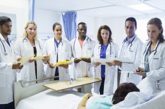 Doctor and residents examining patient in hospital room
