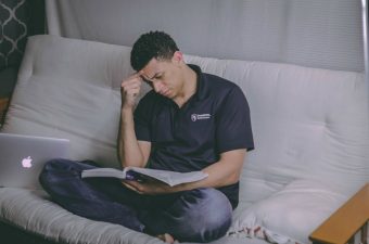 Homem sentado na cama estudanto