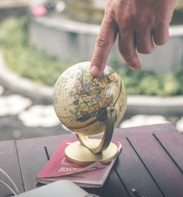 Pessoa com o dedo em um globo terrestre sobre um passaporte