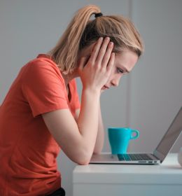 TOEFL ou IELTS: pessoa em frente ao computador segurando a cabeça nas mãos com cara triste
