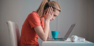 TOEFL ou IELTS: pessoa em frente ao computador segurando a cabeça nas mãos com cara triste