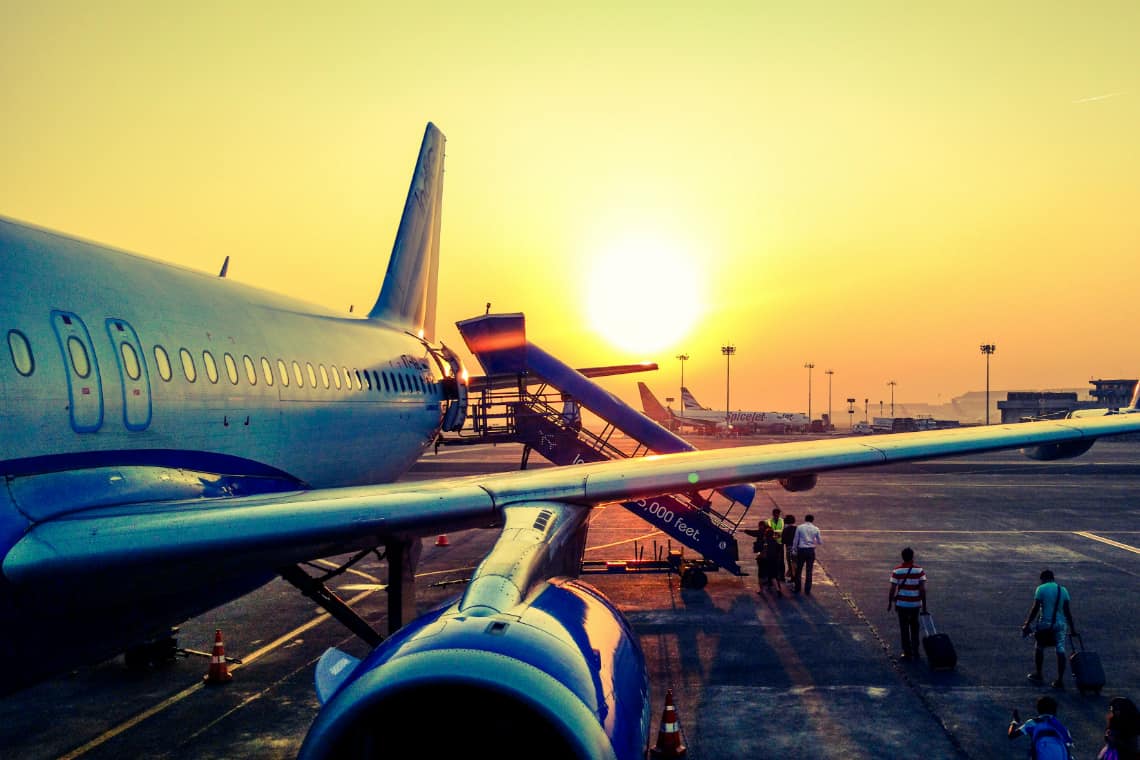 Passagens aéreas mais baratas: imagem de um avião na pista durante o por do sol