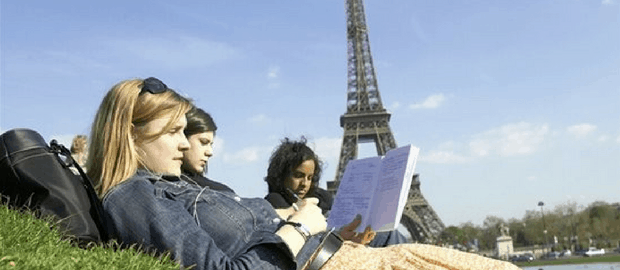 Jovens estudando deitados na grama em frente à torre Eiffel, na França