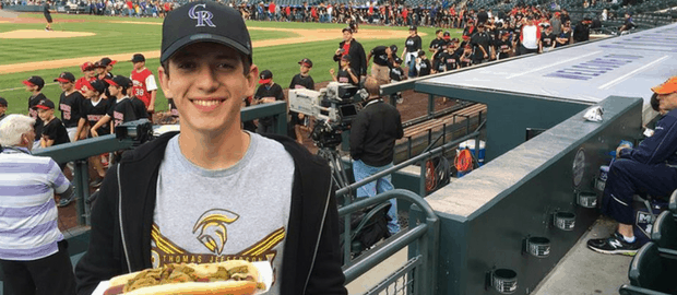 jovem com cachorro quente assistindo jogo de futebol em estádio