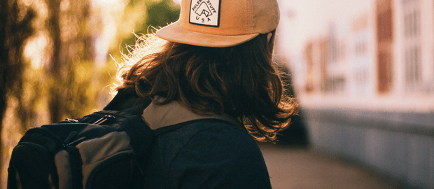 jovem de boné e mochila olhando para o horizonte