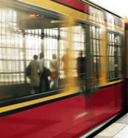 mulher de casaco amarelo olha trem passando em estação