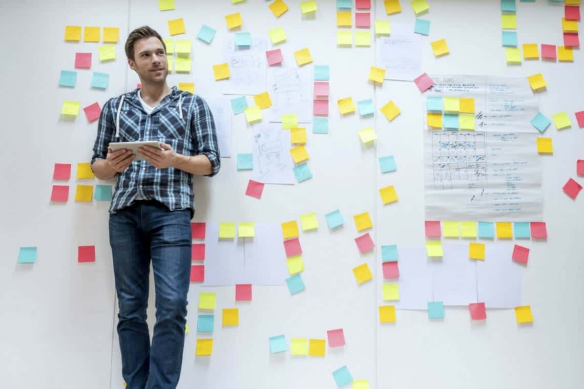 homem empreendedor em frente a quadro de postits