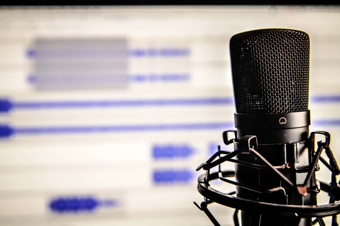 podcasts para aprender inglês: um microfone diante de uma tela de computador com um programa de gravação de áudio
