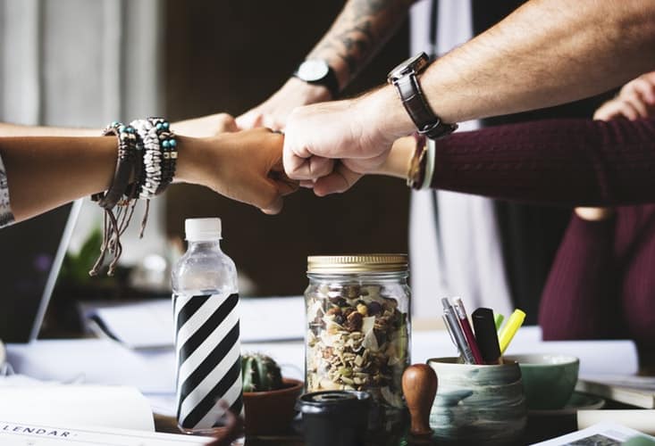 Programa de liderança - pessoas juntando os punhos no centro de uma mesa