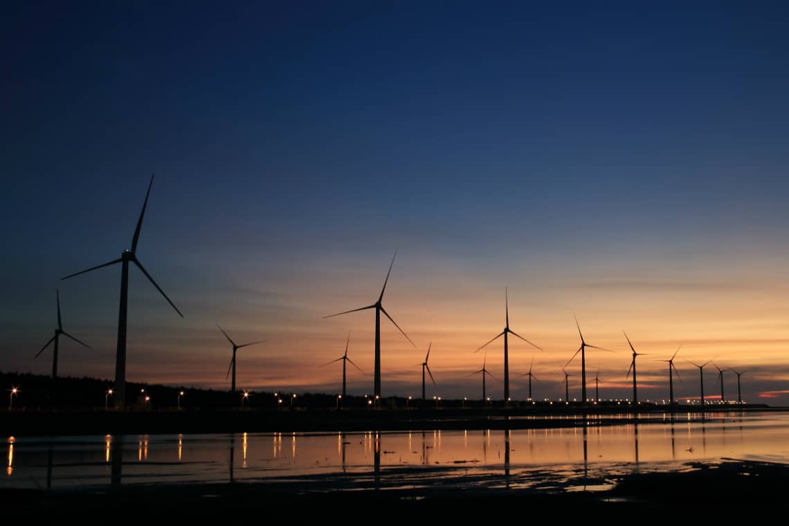 Horizonte durante o pôr do sol, com uma série de turbinas de energia eólica - mestrado em energia sustentável