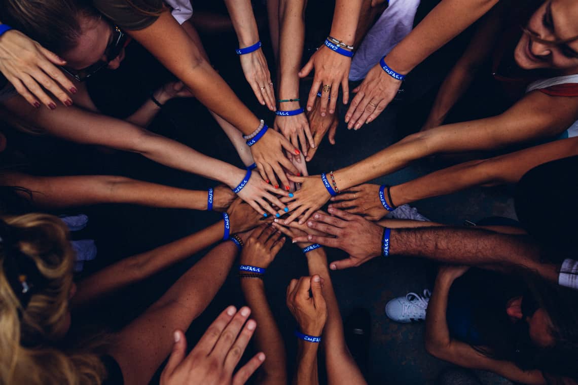 Grupo de pessoas em círculo com as mãos juntas no centro