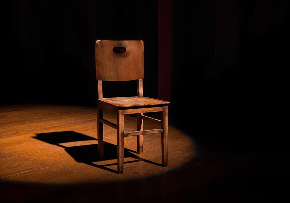 Uma cadeira de madeira iluminada por um holofote