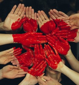 Mãos pintadas de vermelhor formando um coração - trabalho cvoluntário durante o intercâmbio
