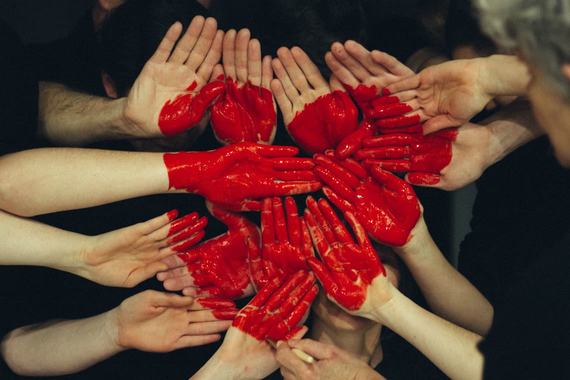 Mãos pintadas de vermelhor formando um coração - trabalho cvoluntário durante o intercâmbio