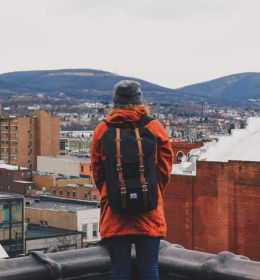 pessoa de mochila em uma varando olhando para uma cidade - como estudar no exterior
