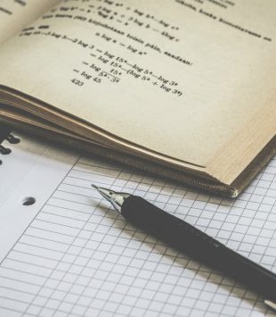 Lapiseira, caderno e um livro de matemática aberto