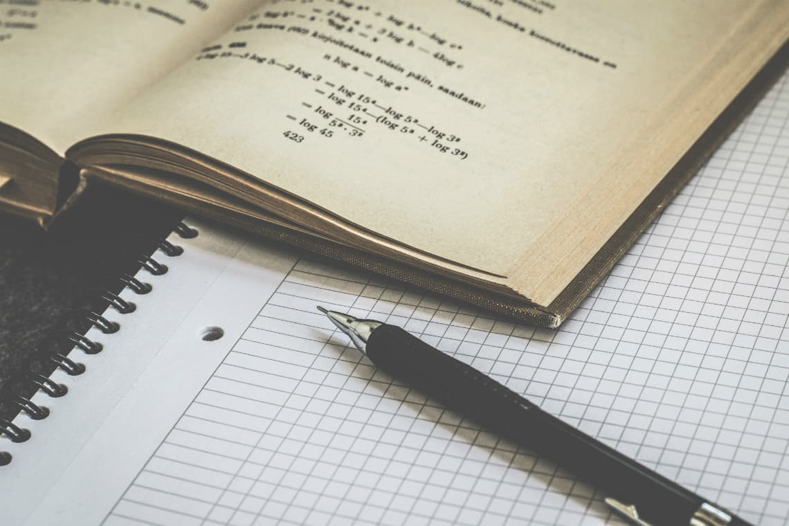 Lapiseira, caderno e um livro de matemática aberto