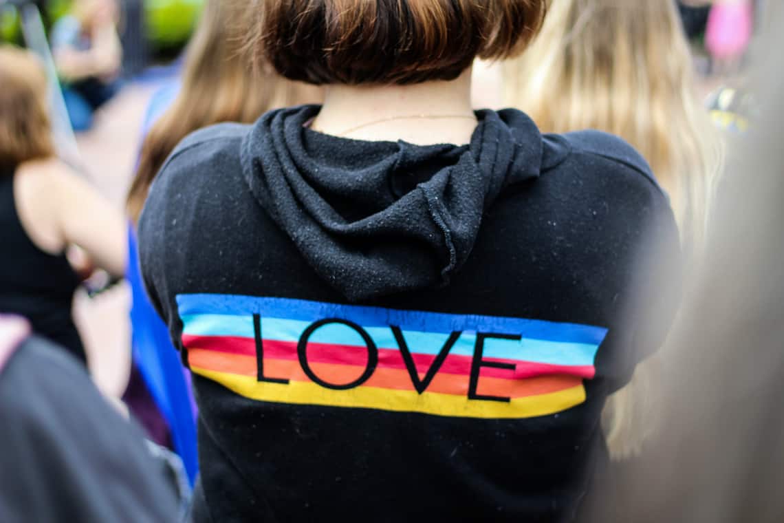 Moça com um moletom preto com um arco-íris escrito LOVE no meio, pride, orgulho, lgbt