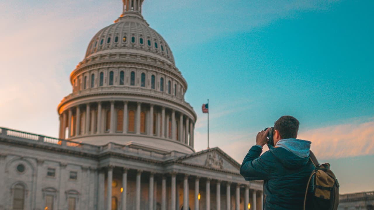 Jovem de mochila tirando foto do capitólio dos UA - Jovens Embaixadores