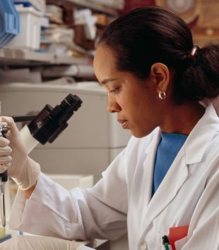Moça usando pipeta em frente a um microscópio - bolsas para mulheres nos EUA