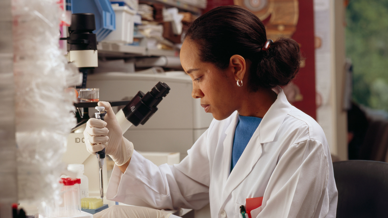 Moça usando pipeta em frente a um microscópio - bolsas para mulheres nos EUA