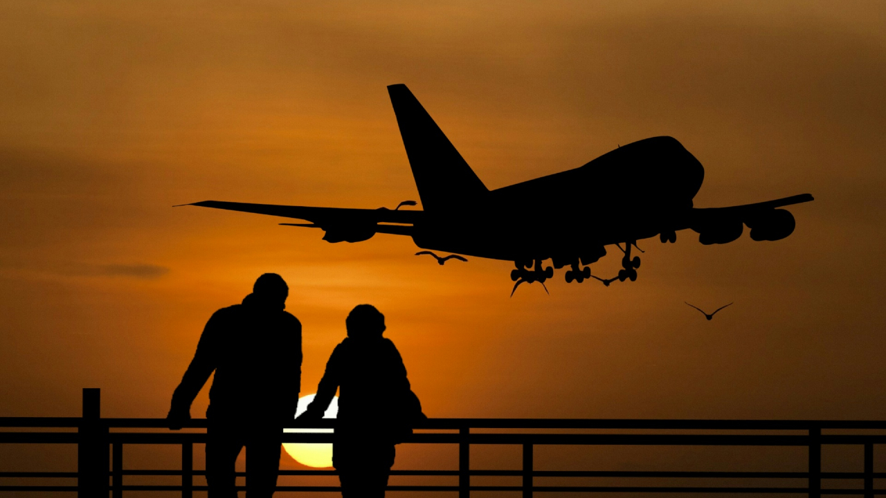 Duas pessoas no por do sol olhando um avião partir - dicas para estudar fora