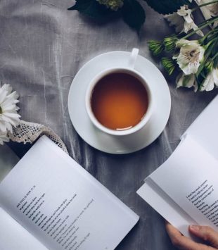 pessoa com dois livros e uma xícara de café na mesa - mestado em literatura comparada
