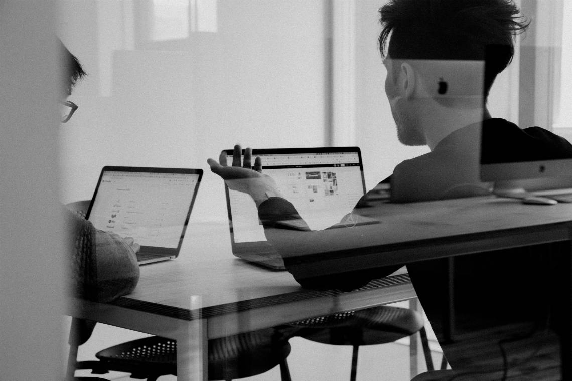 Duas pessoas com computadores em uma sala de reunião, discutindo - comitê de admissões do MBA