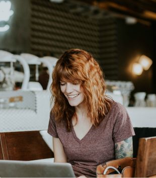 moça olhando notebook num café - cursos online gratuitos