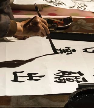 Pessoa escrevendo em mandarim com tinta e pincel