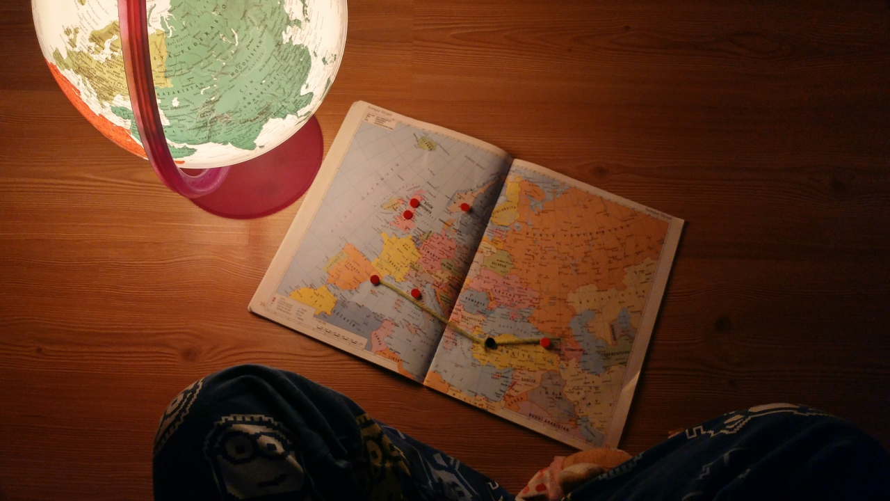 Pessoa sentada em frente a um globo terrestre e um atlas - intercâmbio agora