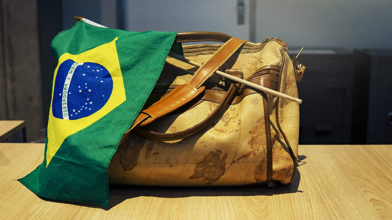 Mala com uma bandeira do Brasil enrolada - brasileiros famosos que estudaram fora