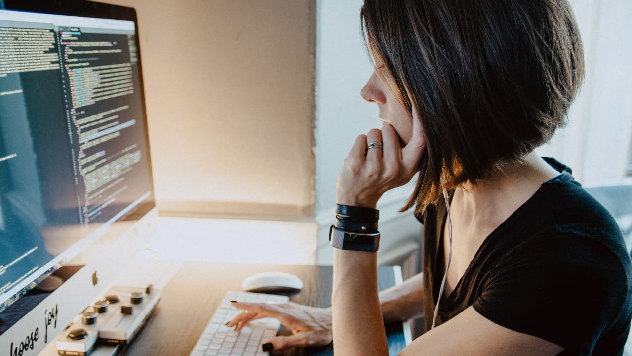 Moça em frente a computador com um monte de código na tela - melhores universidades para estudar ciências da computação