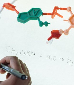 Mão escrevendo num quadro iluminado, com um esquema representando uma molécula em cima - mestrado em nanomedicina