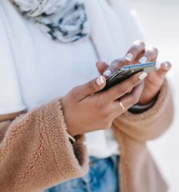 Moça segurando um celular com as duas mãos - apps mais baixados
