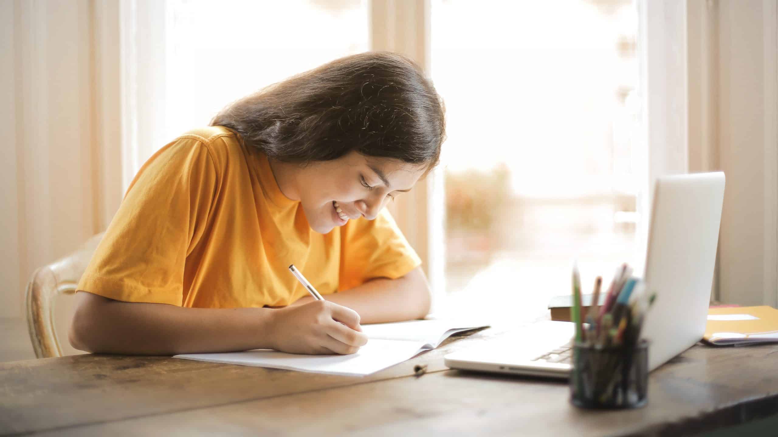 Moça de amarelo estudando, sorrindo - rotina de estudos