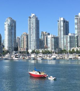 Um barco flutuando em frente a edifícios altos em Vancouver - MBA no Canadá