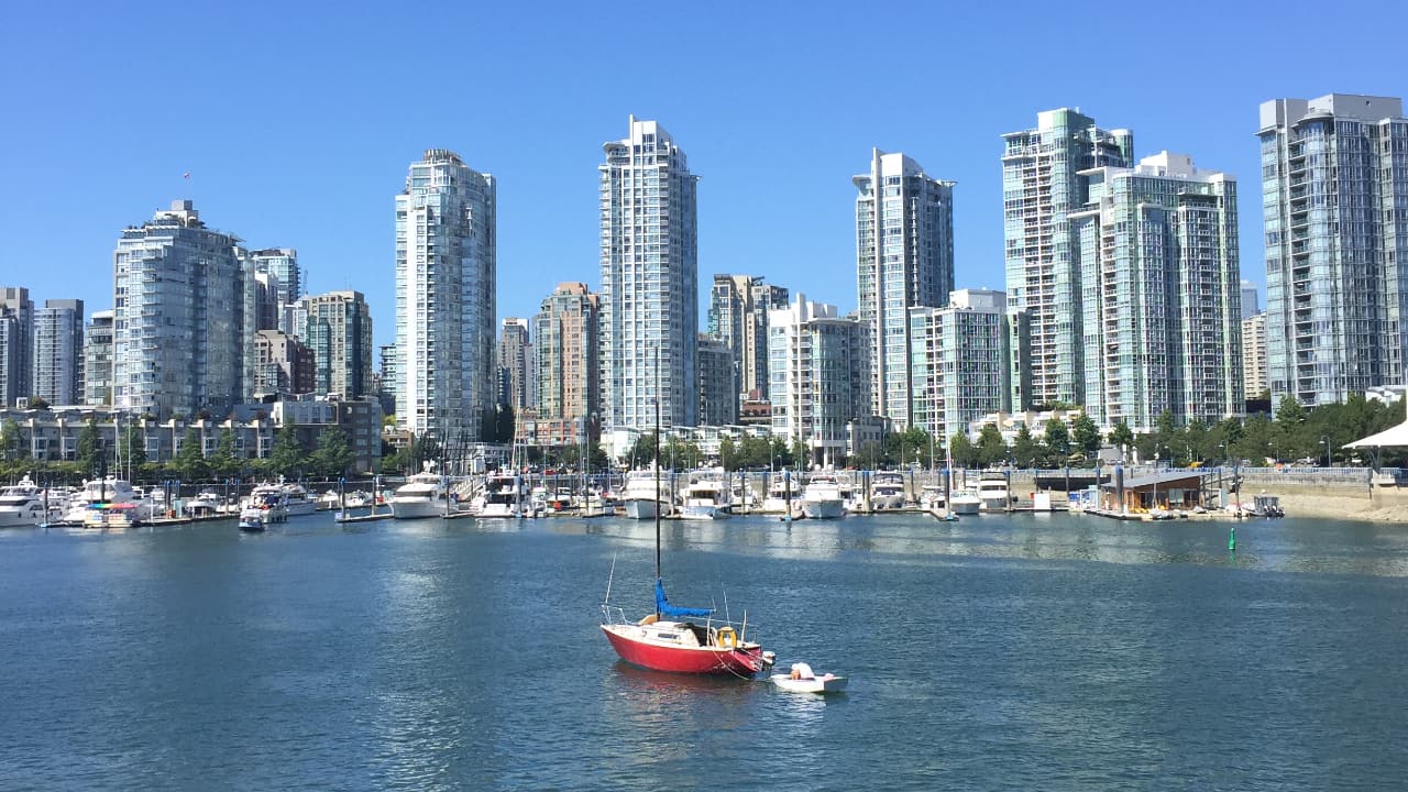 Um barco flutuando em frente a edifícios altos em Vancouver - MBA no Canadá