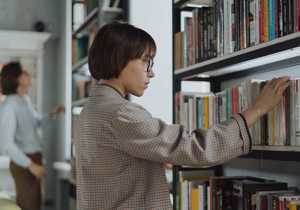 Mulher vendo livros em uma biblioteca