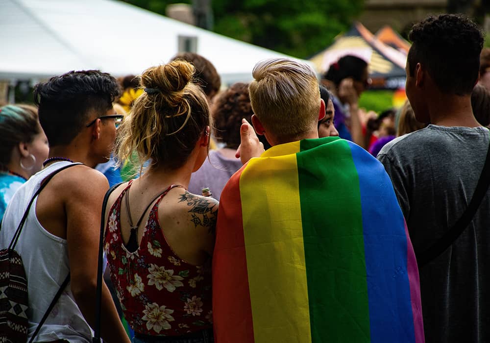 Pessoas de costas com bandeira LGBTQ