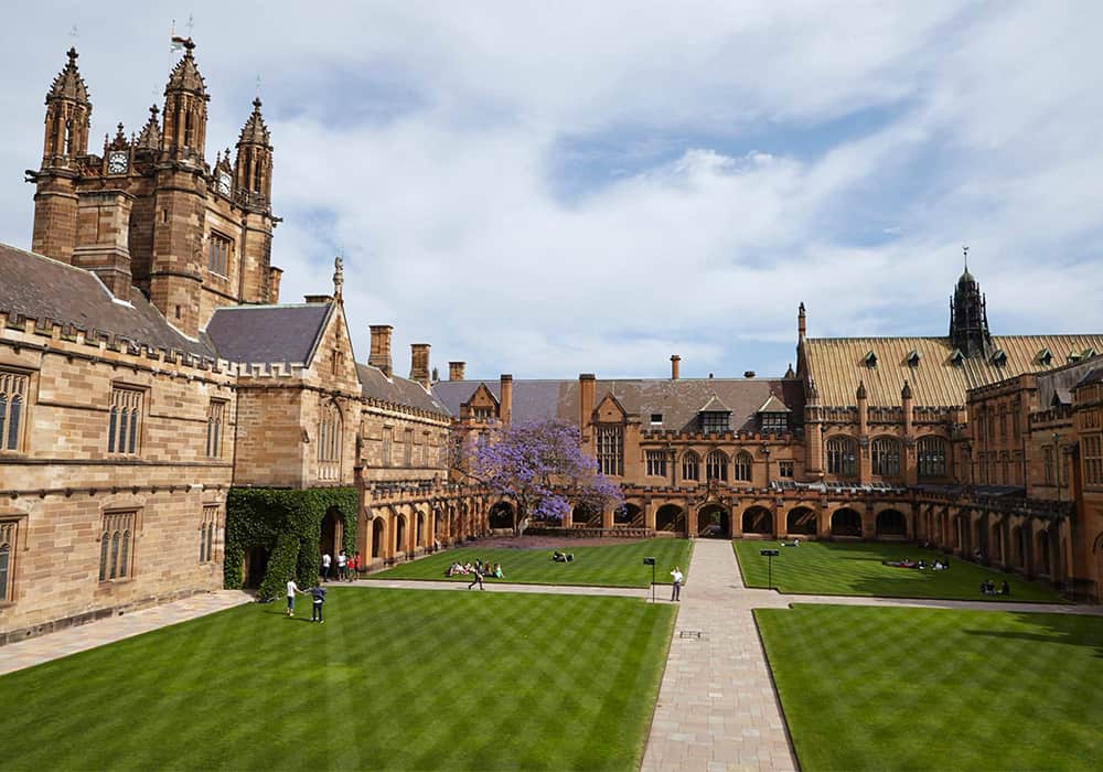 Prédio principal da Universidade de Sydney. Construção em formato de L, com arquitetura antiga.