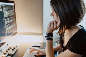 Moça em frente a computador com um monte de código na tela - melhores universidades para estudar ciências da computação