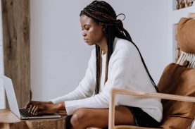 Moça sentada numa poltrona mexendo no computador